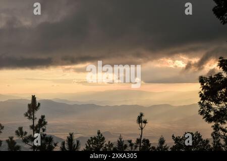 View from the mountains with cloudy skies in the forest during sunset Stock Photo