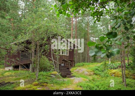 Old wooden cabin in the forest. Vintage retro summer house for vacations, holidays and rest with beautiful natural surrounding Stock Photo