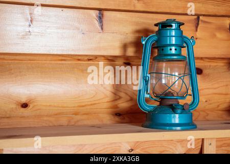 The old vintage retro blue kerosene oil lamp on a wooden shelve inside the wooden countryside house background, banner Stock Photo
