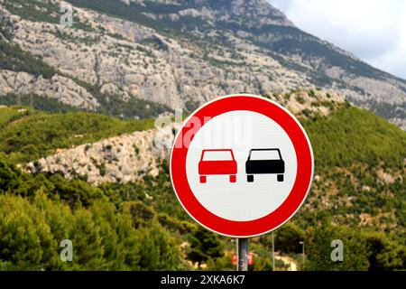 Sign - overtaking is prohibited on the side of a beautiful mountain road in Croatia. Passenger cars are prohibited from overtaking, prohibition road s Stock Photo