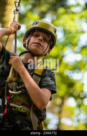 Young adventurer navigating a treetop obstacle course, demonstrating courage and determination. Stock Photo