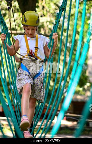 Young adventurer navigating a treetop obstacle course, demonstrating courage and determination. Stock Photo