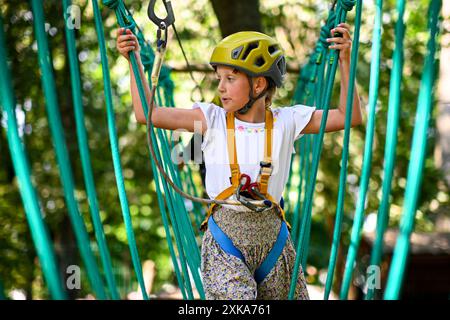 Young adventurer navigating a treetop obstacle course, demonstrating courage and determination. Stock Photo