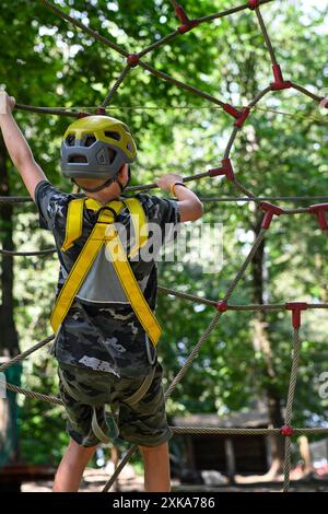 Young adventurer navigating a treetop obstacle course, demonstrating courage and determination. Stock Photo