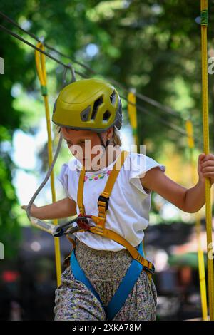 Young adventurer navigating a treetop obstacle course, demonstrating courage and determination. Stock Photo