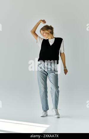 A stylish young woman with blonde hair stands gracefully against a blank backdrop. Stock Photo