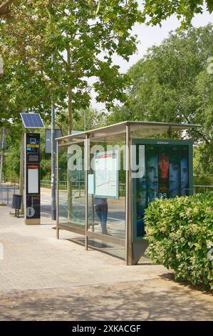 Viladecasn, SPAIN - JULY 22, 2024: Modern bus stop with electronic timetable and route map surrounded by greenery on sunny day. It stands out for its Stock Photo