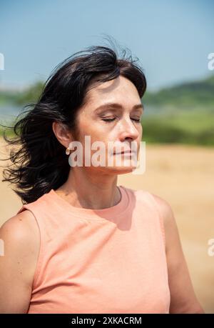 portrait of 50 years old russian woman in and peach fuzz color shirt with eyes closed enjoyng the weather on the summer day Stock Photo