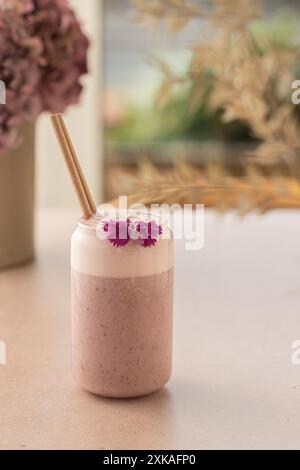 Strawberry vegan smoothie  decorated with coconut and edible flower on a coffee shop table. Stock Photo