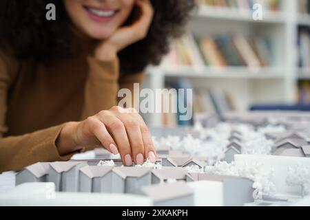 Female architect focused on designing architectural layouts at library desk Stock Photo