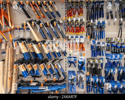 Italy - July 20, 2024: Work hammers and pliers and tongs displayed on shelves for sale in Italian DIY Stock Photo