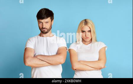 Angry Couple In White Shirts Standing Against Blue Background Stock Photo