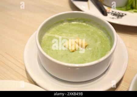 Green spinach soup in a white bowl with a saucer on the dining table. And there was tuna salad on a white plate nearby. Stock Photo