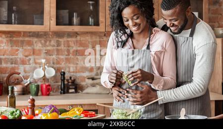 Husband hugging his wife from behind while cooking Stock Photo