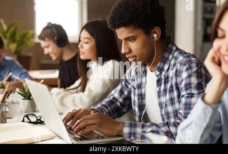 Student learning lessons in school library, using laptop Stock Photo