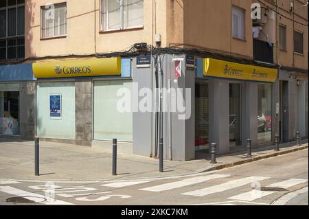 Viladecasn, SPAIN - JULY 22, 2024: An image of a post office located on the corner of an urban street. The building has frosted glass windows and a ye Stock Photo