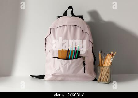 School backpack and school stupplies with space for products on wooden desk on white wall background. Back to school concept. Copy space Stock Photo