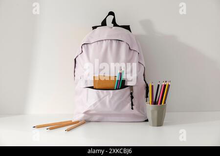 School backpack and school stupplies with space for products on wooden desk on white wall background. Back to school concept. Copy space Stock Photo