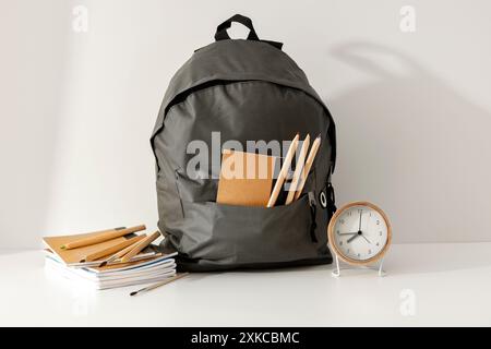 School backpack and school stupplies with space for products on wooden desk on white wall background. Back to school concept. Copy space Stock Photo