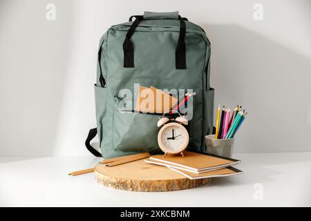 School backpack and school stupplies with space for products on wooden desk on white wall background. Back to school concept. Copy space Stock Photo