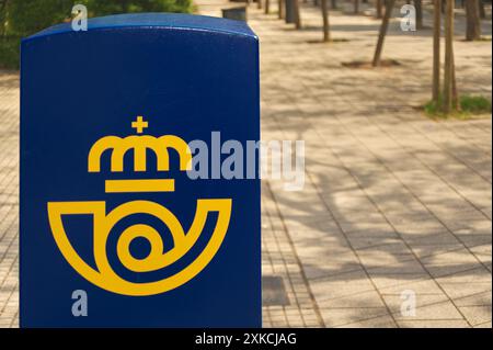 Viladecasn, SPAIN - JULY 22, 2024: Image of a blue postal mailbox featuring a yellow emblem symbolizing a crown, located in an urban setting. This mai Stock Photo