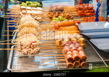 Assorted skewers with various meats, vegetables, and mushrooms displayed on food stall grill on night food market, Phuket, Thailand. Thai street food Stock Photo