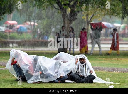 New Delhi, India. 22nd July, 2024. NEW DELHI, INDIA - JULY 22: People take shelter under a tarpaulin as heavy rain lashes in different parts of the city, at Kartavya Path, on July 22, 2024 in New Delhi, India. Delhi residents witnessed a sudden change in weather as heavy rain lashed several parts of the city on Monday afternoon. The people got relief from a prolonged spell of humid conditions. However, several areas in the national capital were waterlogged. (Photo by Arvind Yadav/Hindustan Times/Sipa USA ) Credit: Sipa USA/Alamy Live News Stock Photo