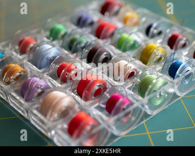 Bobbins with colored threads in the plastic box for storage, selective focus. Sewing accessories concept Stock Photo