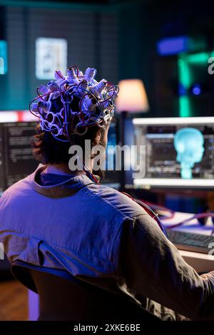 Software engineer using EEG headset translating thoughts into PC commands using brainwave signals. IT admin controlling computer functions using mind, helped by biosensor technology research Stock Photo
