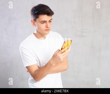 Emotional male student writing message on smartphone screen Stock Photo