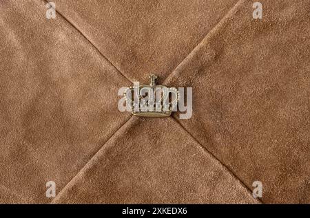 Photo texture of brown colored sewn suede leather material with copper crown element. Stock Photo