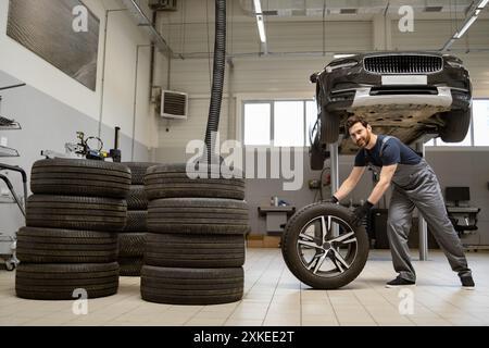 Mechanic in auto repair shop changing car tire with new wheel Stock Photo
