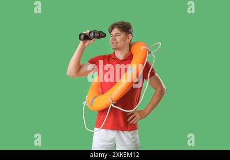 Male lifeguard with binoculars and ring buoy on green background Stock Photo