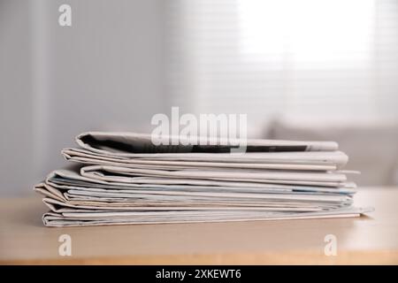 Stack of newspapers in different languages on table indoors Stock Photo