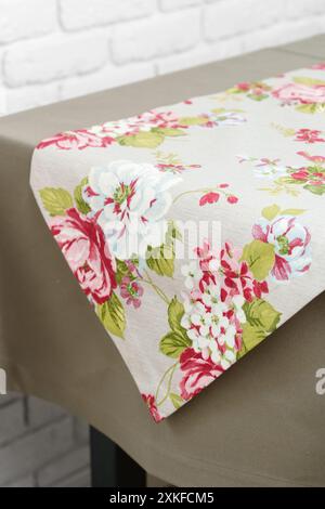 Floral Table Runner on a Beige Tablecloth Against a White Brick Wall Stock Photo