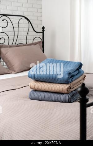 Stacked Blue and Beige Blankets on a Made Bed Stock Photo