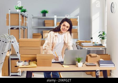 Happy young business woman and logistic manager is working in her small warehouse Stock Photo