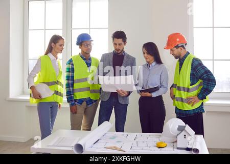 Team of architects and builders meeting in office and discussing construction plan Stock Photo