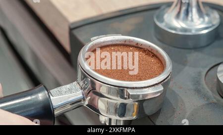 Close-up of a portafilter with perfectly tamped coffee grounds, ready for brewing a rich espresso shot in a coffee machine. Stock Photo
