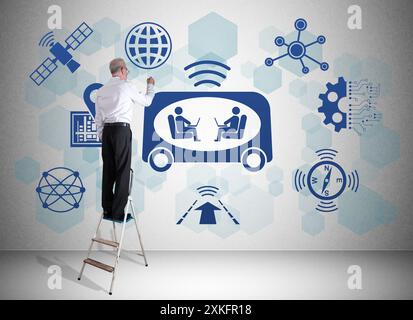 Man on a ladder drawing self-driving car concept on a wall Stock Photo