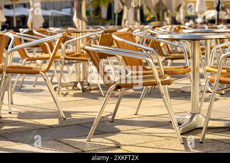 Many wicker chairs at cafe tables in the morning sun. Stock Photo