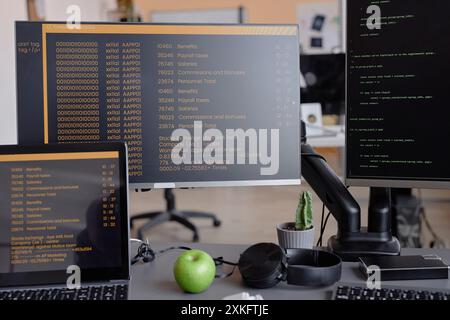 Still-life shot of software developer workspace with computer and laptop monitors displaying coding language program on black background in company office Stock Photo