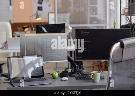 Interior of empty modern software developer office with computers on desk programming language on screen Stock Photo