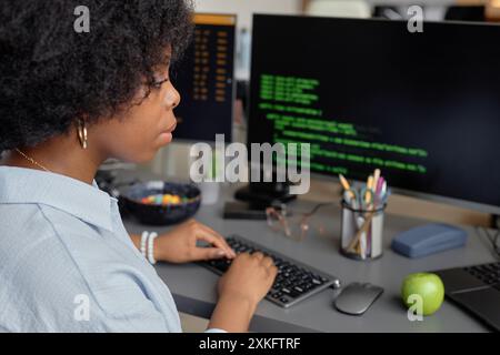 Side view of young African American software developer typing on keyboard while writing code for application in modern office, copy space Stock Photo