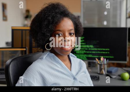 Close up portrait of young Black woman working as IT technician in contemporary office with multiple computer screens smiling while looking at camera, copy space Stock Photo
