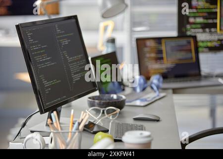 Background shot of software engineer working desk with multiple computer screens displaying programming code in IT office, copy space Stock Photo