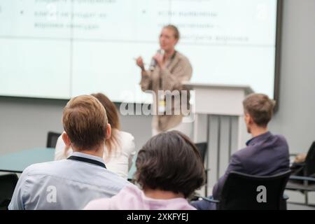 Audience attending business presentation in modern office setting, focused on speaker delivering a speech Stock Photo