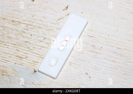 A negative pregnancy test is shown lying on a wooden surface, possibly symbolizing a lack of desired outcome. The image depicts a blend of technology Stock Photo