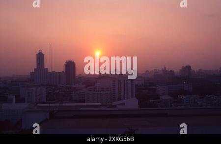Sunrise over Bangkok, Thailand in 1992 – a misty morning view of the sun rising through atmospheric haze above the developing city skyline, captured in the early 1990s. Stock Photo