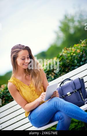 Woman, park and happy with tablet for online dating or social media for networking and fun. Female person, outdoor and smile with waiting for date on Stock Photo